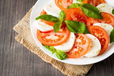 Caprese salatası olgun domates, fesleğen, buffalo mozzarella peyniri ile yakın çekim fotoğraf. İtalyan ve Akdeniz gıda kavramı. Taze ve sağlıklı organik yemek. Starter ve antipasti. 