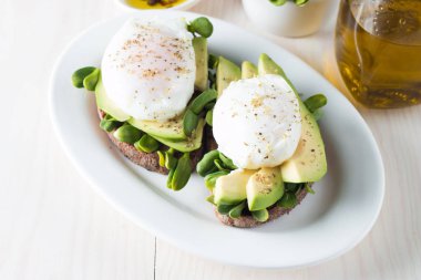 Avokado tost, kiraz domates ahşap arka plan üzerinde. Kahvaltı tost avokado, Vejetaryen gıda, sağlıklı beslenme kavramı ile. Avokado ve haşlanmış yumurta ile sağlıklı sandviç.