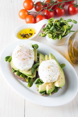 Avokado tost, kiraz domates ahşap arka plan üzerinde. Kahvaltı tost avokado, Vejetaryen gıda, sağlıklı beslenme kavramı ile. Avokado ve haşlanmış yumurta ile sağlıklı sandviç.