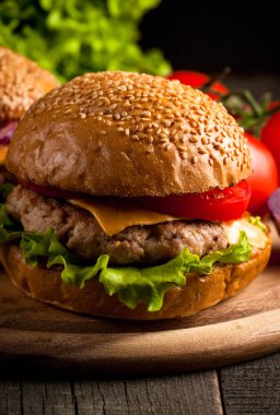 Ev yapımı Hamburger bira ile yakın çekim fotoğraf sığır eti, soğan, domates, marul, peynir ve baharat yaptı. Taze hamburger tatlı patates kızartması ve cips ile ahşap rustik tabloda.