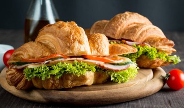 Taze kruvasan veya sandviç salata, jambon, jamon, jambon, salam, peynir, tavuk, domates ahşap arka plan ile. Sabah kahvaltı kavramı. Sağlıklı ve fast food.