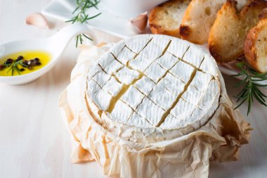 Pişmiş camembert peyniri. Taze Brie peyniri ve bir dilim fındık, tatlım, biberiye ile ahşap bir gemide, baget ekmek ızgara tost ve yaprakları. Peynir Brie türü. İtalyan, Fransız peynir.