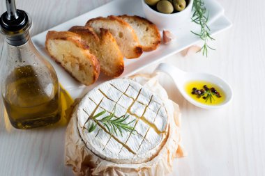 Pişmiş camembert peyniri. Taze Brie peyniri ve bir dilim fındık, tatlım, biberiye ile ahşap bir gemide, baget ekmek ızgara tost ve yaprakları. Peynir Brie türü. İtalyan, Fransız peynir.