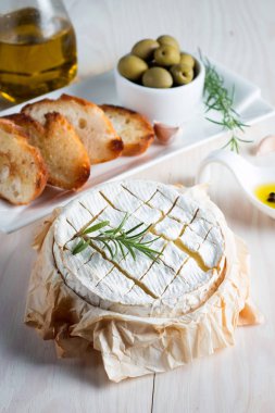 Pişmiş camembert peyniri. Taze Brie peyniri ve bir dilim fındık, tatlım, biberiye ile ahşap bir gemide, baget ekmek ızgara tost ve yaprakları. Peynir Brie türü. İtalyan, Fransız peynir.