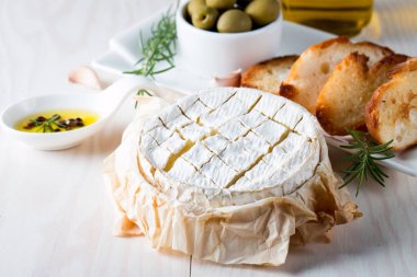 Pişmiş camembert peyniri. Taze Brie peyniri ve bir dilim fındık, tatlım, biberiye ile ahşap bir gemide, baget ekmek ızgara tost ve yaprakları. Peynir Brie türü. İtalyan, Fransız peynir.