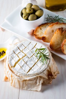 Pişmiş camembert peyniri. Taze Brie peyniri ve bir dilim fındık, tatlım, biberiye ile ahşap bir gemide, baget ekmek ızgara tost ve yaprakları. Peynir Brie türü. İtalyan, Fransız peynir.