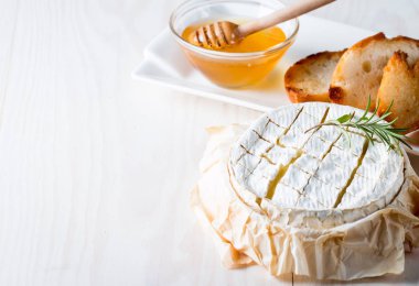 Pişmiş camembert peyniri. Taze Brie peyniri ve bir dilim fındık, tatlım, biberiye ile ahşap bir gemide, baget ekmek ızgara tost ve yaprakları. Peynir Brie türü. İtalyan, Fransız peynir.