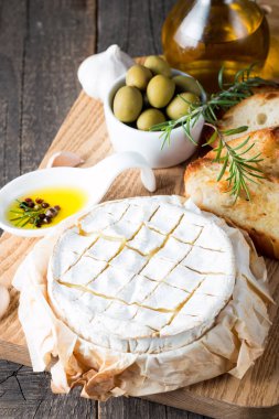 Pişmiş camembert peyniri. Taze Brie peyniri ve bir dilim fındık, tatlım, biberiye ile ahşap bir gemide, baget ekmek ızgara tost ve yaprakları. Peynir Brie türü. İtalyan, Fransız peynir.