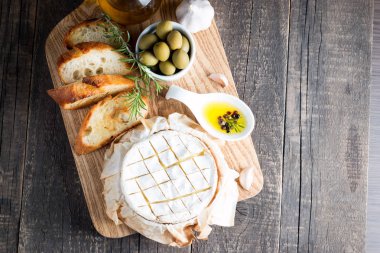 Pişmiş camembert peyniri. Taze Brie peyniri ve bir dilim fındık, tatlım, biberiye ile ahşap bir gemide, baget ekmek ızgara tost ve yaprakları. Peynir Brie türü. İtalyan, Fransız peynir.