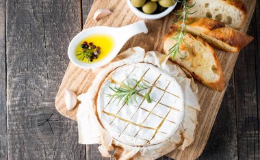 Pişmiş camembert peyniri. Taze Brie peyniri ve bir dilim fındık, tatlım, biberiye ile ahşap bir gemide, baget ekmek ızgara tost ve yaprakları. Peynir Brie türü. İtalyan, Fransız peynir.