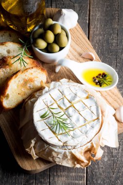 Pişmiş camembert peyniri. Taze Brie peyniri ve bir dilim fındık, tatlım, biberiye ile ahşap bir gemide, baget ekmek ızgara tost ve yaprakları. Peynir Brie türü. İtalyan, Fransız peynir.