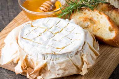 Pişmiş camembert peyniri. Taze Brie peyniri ve bir dilim fındık, tatlım, biberiye ile ahşap bir gemide, baget ekmek ızgara tost ve yaprakları. Peynir Brie türü. İtalyan, Fransız peynir.