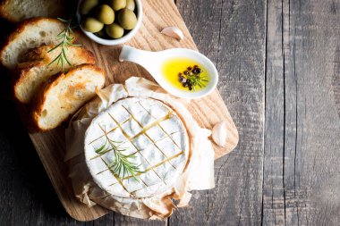 Pişmiş camembert peyniri. Taze Brie peyniri ve bir dilim fındık, tatlım, biberiye ile ahşap bir gemide, baget ekmek ızgara tost ve yaprakları. Peynir Brie türü. İtalyan, Fransız peynir.
