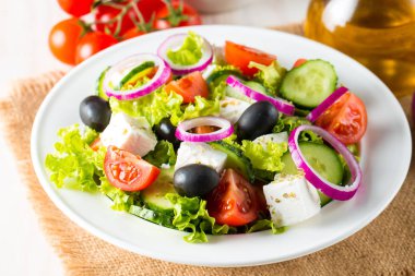 Kiraz domates, ruccola, roka, beyaz peynir, zeytin, salatalık, soğan ve baharat taze Yunan salatası yaptı. Sezar salatası ahşap arka plan üzerinde beyaz bir kase. Sağlıklı organik beslenme gıda kavramı.