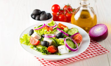 Kiraz domates, ruccola, roka, beyaz peynir, zeytin, salatalık, soğan ve baharat taze Yunan salatası yaptı. Sezar salatası ahşap arka plan üzerinde beyaz bir kase. Sağlıklı organik beslenme gıda kavramı.