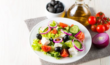 Kiraz domates, ruccola, roka, beyaz peynir, zeytin, salatalık, soğan ve baharat taze Yunan salatası yaptı. Sezar salatası ahşap arka plan üzerinde beyaz bir kase. Sağlıklı organik beslenme gıda kavramı.