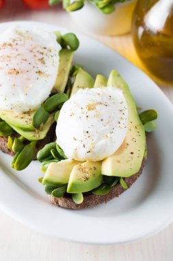 Avokado tost, kiraz domates ahşap arka plan üzerinde. Kahvaltı tost avokado, Vejetaryen gıda, sağlıklı beslenme kavramı ile. Avokado ve haşlanmış yumurta ile sağlıklı sandviç.