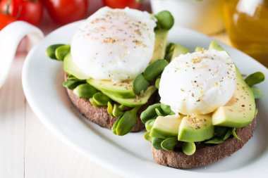 Avokado tost, kiraz domates ahşap arka plan üzerinde. Kahvaltı tost avokado, Vejetaryen gıda, sağlıklı beslenme kavramı ile. Avokado ve haşlanmış yumurta ile sağlıklı sandviç.
