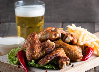 Yakın çekim fotoğraf Barbekü tavuk kanatlı patates ve bira. Barbekü soslar, ketçap, mayonez etli. Hızlı ve abur cubur kavramı. 