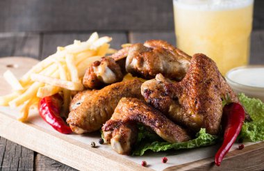 Yakın çekim fotoğraf Barbekü tavuk kanatlı patates ve bira. Barbekü soslar, ketçap, mayonez etli. Hızlı ve abur cubur kavramı. 