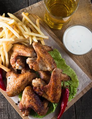 Yakın çekim fotoğraf Barbekü tavuk kanatlı patates ve bira. Barbekü soslar, ketçap, mayonez etli. Hızlı ve abur cubur kavramı. 