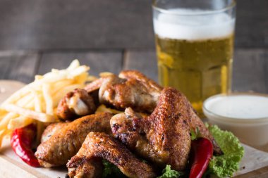 Yakın çekim fotoğraf Barbekü tavuk kanatlı patates ve bira. Barbekü soslar, ketçap, mayonez etli. Hızlı ve abur cubur kavramı. 