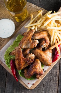 Yakın çekim fotoğraf Barbekü tavuk kanatlı patates ve bira. Barbekü soslar, ketçap, mayonez etli. Hızlı ve abur cubur kavramı. 