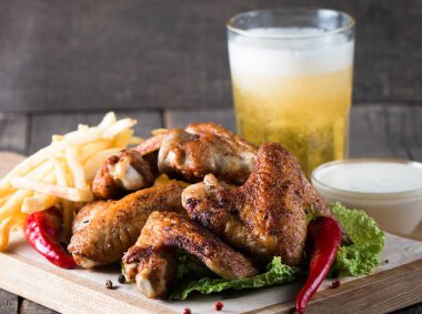 Yakın çekim fotoğraf Barbekü tavuk kanatlı patates ve bira. Barbekü soslar, ketçap, mayonez etli. Hızlı ve abur cubur kavramı. 