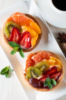 Taze meyve ve meyve ahşap zemin üzerine atmak şekerli tatlı tart. Ahududu, üzüm, çilek, kiraz, kivi, greyfurt ve krema ile lezzetli tatlı pasta.