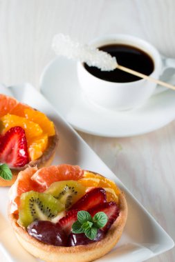 Taze meyve ve meyve ahşap zemin üzerine atmak şekerli tatlı tart. Ahududu, üzüm, çilek, kiraz, kivi, greyfurt ve krema ile lezzetli tatlı pasta.