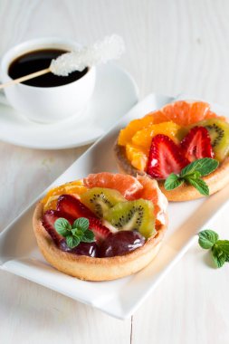 Taze meyve ve meyve ahşap zemin üzerine atmak şekerli tatlı tart. Ahududu, üzüm, çilek, kiraz, kivi, greyfurt ve krema ile lezzetli tatlı pasta.