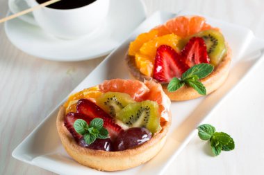 Taze meyve ve meyve ahşap zemin üzerine atmak şekerli tatlı tart. Ahududu, üzüm, çilek, kiraz, kivi, greyfurt ve krema ile lezzetli tatlı pasta.