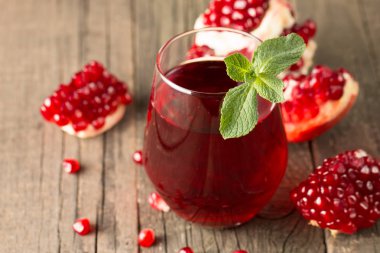 Bir bardak nar suyu ve ahşap masada taze nar meyveleri. Vitamin ve mineraller. Sağlıklı içki konsepti.