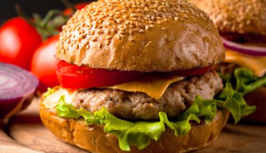 Ev yapımı Hamburger bira ile yakın çekim fotoğraf sığır eti, soğan, domates, marul, peynir ve baharat yaptı. Taze hamburger tatlı patates kızartması ve cips ile ahşap rustik tabloda.