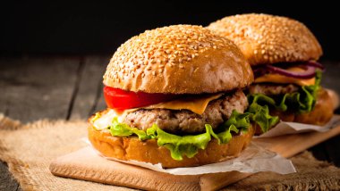 Ev yapımı Hamburger bira ile yakın çekim fotoğraf sığır eti, soğan, domates, marul, peynir ve baharat yaptı. Taze hamburger tatlı patates kızartması ve cips ile ahşap rustik tabloda.