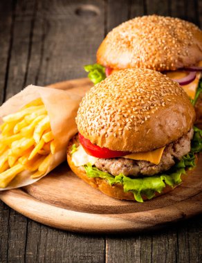 Ev yapımı Hamburger bira ile yakın çekim fotoğraf sığır eti, soğan, domates, marul, peynir ve baharat yaptı. Taze hamburger tatlı patates kızartması ve cips ile ahşap rustik tabloda.