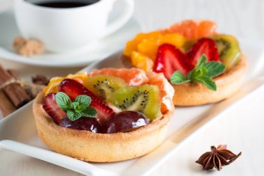 Taze meyve ve meyve ahşap zemin üzerine atmak şekerli tatlı tart. Ahududu, üzüm, çilek, kiraz, kivi, greyfurt ve krema ile lezzetli tatlı pasta.