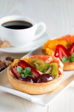 Taze meyve ve meyve ahşap zemin üzerine atmak şekerli tatlı tart. Ahududu, üzüm, çilek, kiraz, kivi, greyfurt ve krema ile lezzetli tatlı pasta.