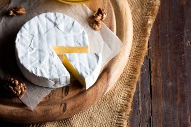 Brie peyniri. Camembert peyniri. Taze Brie peyniri ve tahtadan bir dilim fındık, bal ve yaprakla. İtalyan, Fransız peyniri.