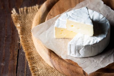 Brie peyniri. Camembert peyniri. Taze Brie peyniri ve tahtadan bir dilim fındık, bal ve yaprakla. İtalyan, Fransız peyniri.