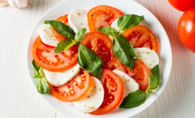 Caprese salatası olgun domates, fesleğen, buffalo mozzarella peyniri ile yakın çekim fotoğraf. İtalyan ve Akdeniz gıda kavramı. Taze ve sağlıklı organik yemek. Starter ve antipasti. 