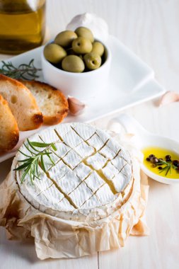 Pişmiş camembert peyniri. Taze Brie peyniri ve bir dilim fındık, tatlım, biberiye ile ahşap bir gemide, baget ekmek ızgara tost ve yaprakları. Peynir Brie türü. İtalyan, Fransız peynir.