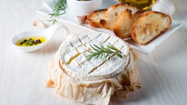 Pişmiş camembert peyniri. Taze Brie peyniri ve bir dilim fındık, tatlım, biberiye ile ahşap bir gemide, baget ekmek ızgara tost ve yaprakları. Peynir Brie türü. İtalyan, Fransız peynir.