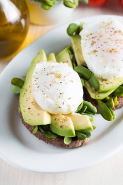 Avokado tost, kiraz domates ahşap arka plan üzerinde. Kahvaltı tost avokado, Vejetaryen gıda, sağlıklı beslenme kavramı ile. Avokado ve haşlanmış yumurta ile sağlıklı sandviç.