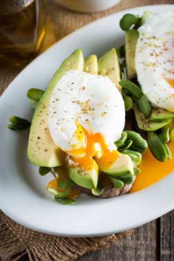 Avokado tost, kiraz domates ahşap arka plan üzerinde. Kahvaltı tost avokado, Vejetaryen gıda, sağlıklı beslenme kavramı ile. Avokado ve haşlanmış yumurta ile sağlıklı sandviç.