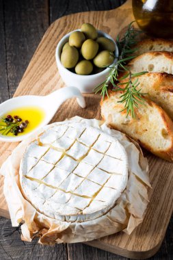 Pişmiş camembert peyniri. Taze Brie peyniri ve bir dilim fındık, tatlım, biberiye ile ahşap bir gemide, baget ekmek ızgara tost ve yaprakları. Peynir Brie türü. İtalyan, Fransız peynir.