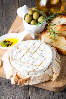 Pişmiş camembert peyniri. Taze Brie peyniri ve bir dilim fındık, tatlım, biberiye ile ahşap bir gemide, baget ekmek ızgara tost ve yaprakları. Peynir Brie türü. İtalyan, Fransız peynir.