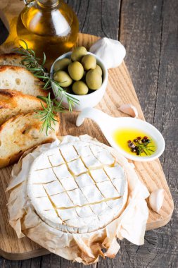 Pişmiş camembert peyniri. Taze Brie peyniri ve bir dilim fındık, tatlım, biberiye ile ahşap bir gemide, baget ekmek ızgara tost ve yaprakları. Peynir Brie türü. İtalyan, Fransız peynir.