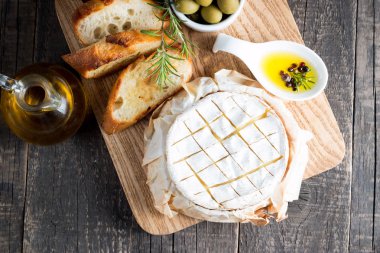 Pişmiş camembert peyniri. Taze Brie peyniri ve bir dilim fındık, tatlım, biberiye ile ahşap bir gemide, baget ekmek ızgara tost ve yaprakları. Peynir Brie türü. İtalyan, Fransız peynir.