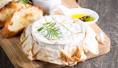 Pişmiş camembert peyniri. Taze Brie peyniri ve bir dilim fındık, tatlım, biberiye ile ahşap bir gemide, baget ekmek ızgara tost ve yaprakları. Peynir Brie türü. İtalyan, Fransız peynir.